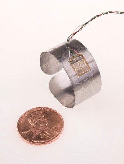 A silver-colored ring with multi-colored wires attached, next to a penny for scale.